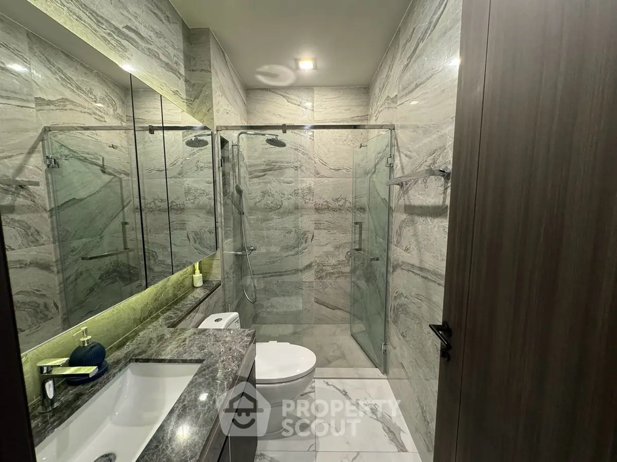 Luxurious modern bathroom with marble tiles and glass shower enclosure