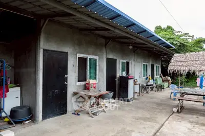 Rustic exterior view of rural housing with corrugated metal roof and outdoor seating area.
