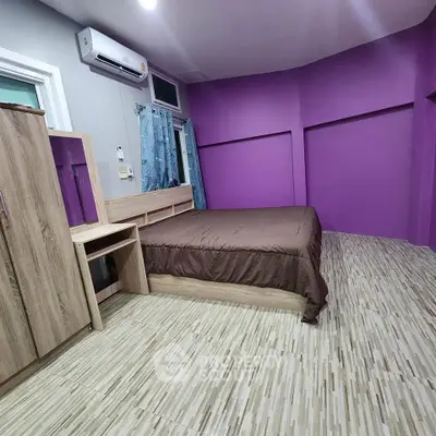 Modern bedroom with vibrant purple accent wall and sleek wooden furniture.