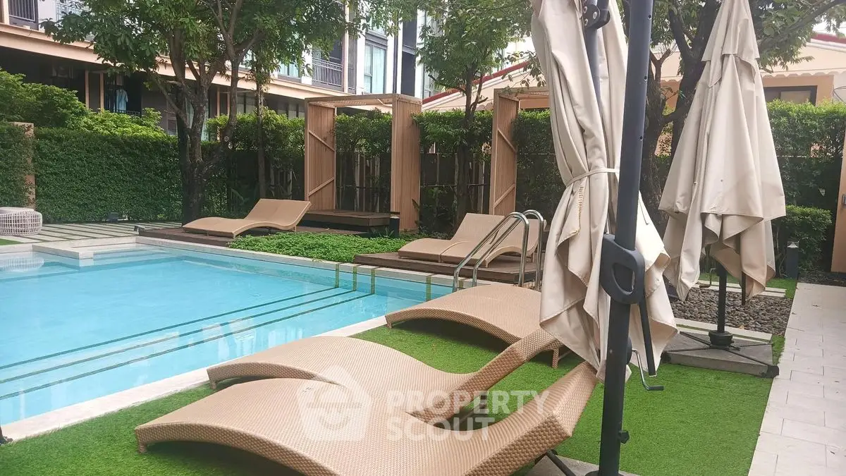 Luxurious poolside area with modern loungers and lush greenery in a serene residential complex.