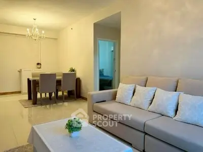 Elegant living room with cozy beige sofa and stylish dining area under a chandelier.