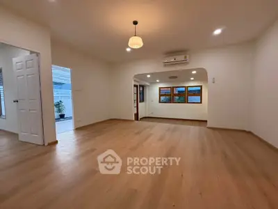Spacious living room with wooden flooring and modern lighting in a bright, open layout home.