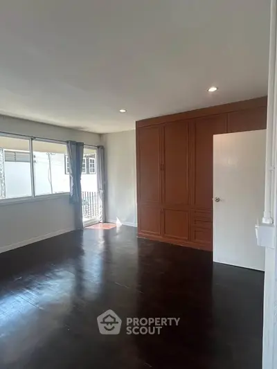 Spacious bedroom with dark wood flooring and large windows for natural light.