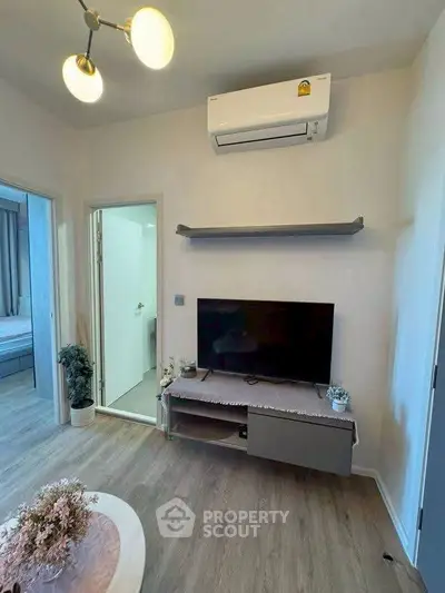 Modern living room with air conditioning and TV, featuring stylish decor and wooden flooring.