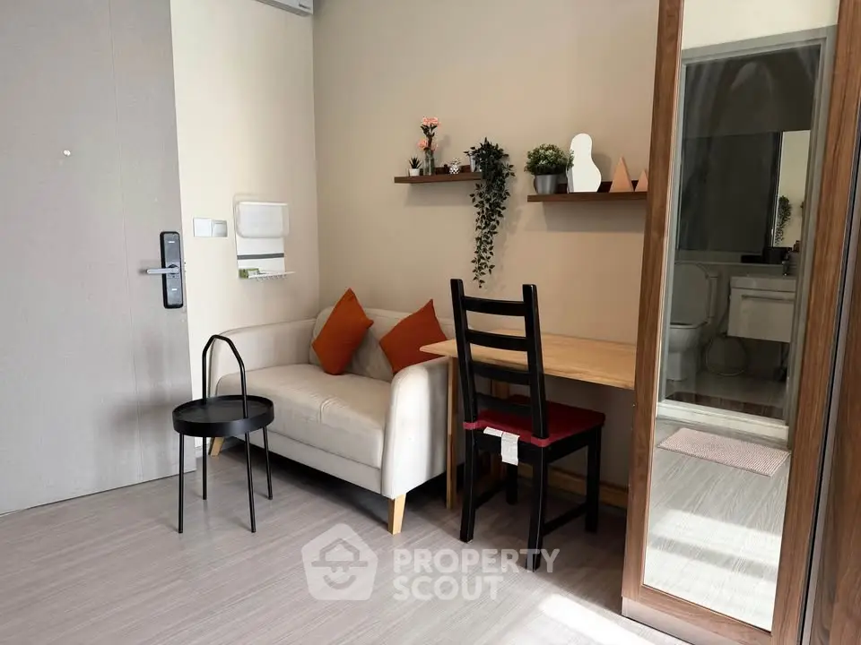 Cozy living room with modern decor and natural light, featuring a small sofa and dining area.