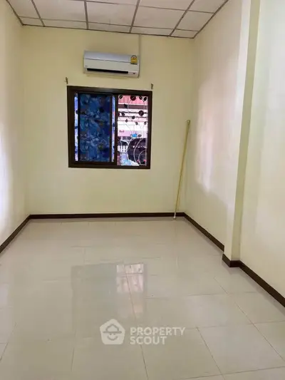 Spacious empty room with tiled floor and air conditioning, ready for customization.