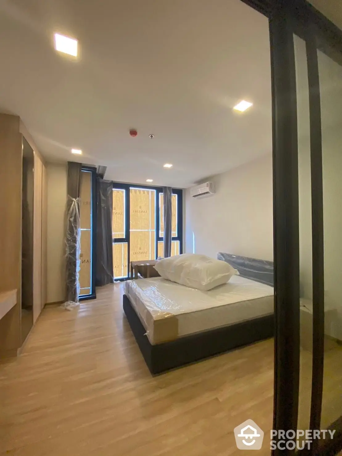 Spacious bedroom with large windows allowing ample natural light, modern flooring, and a comfortable bed ready for a restful night's sleep.