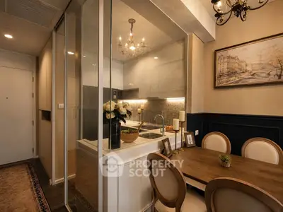 Elegant dining area with glass-enclosed kitchen, chandelier, and classic decor in a cozy apartment setting.