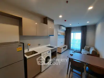 Modern apartment interior with kitchen and living area featuring washing machine and fridge.