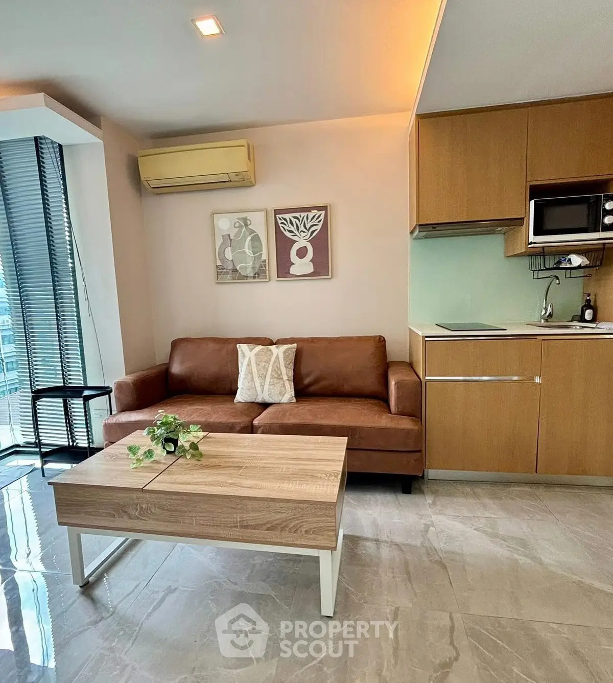 Modern living room with leather sofa and compact kitchen in stylish apartment.