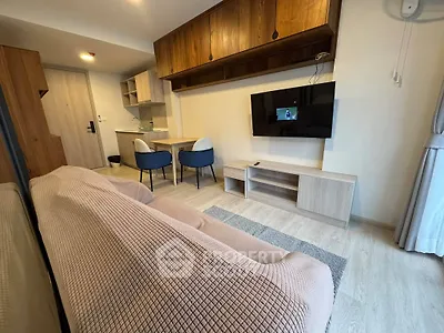 Modern living room with cozy sofa, wall-mounted TV, and dining area in open layout apartment.