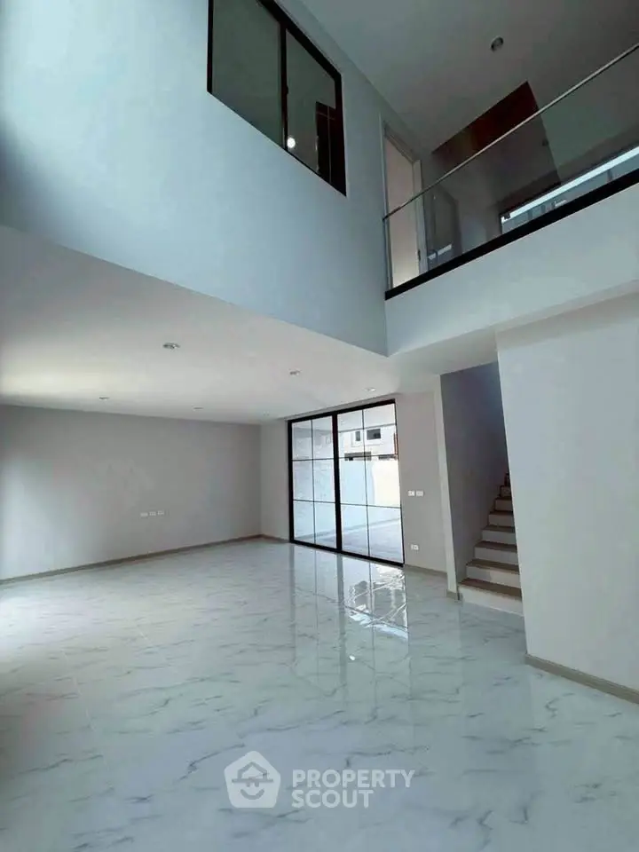 Spacious modern living room with high ceiling and elegant staircase