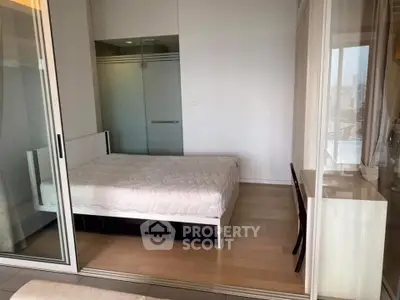 Modern bedroom with glass partition and city view, featuring a cozy bed and sleek wooden flooring.