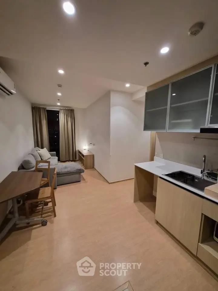 Modern open-plan living room with kitchen, featuring sleek design and cozy seating area.
