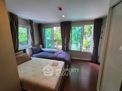 Spacious bedroom with large windows and garden view, featuring comfortable beds and elegant curtains.