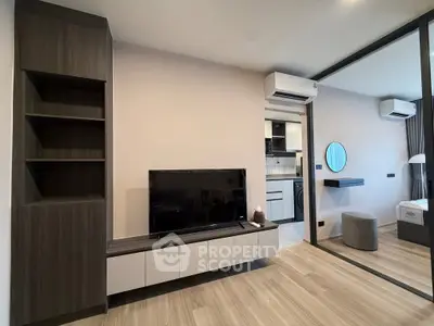 Modern living room with sleek TV unit and open kitchen layout in stylish apartment.