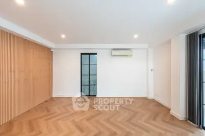 Spacious modern living room with herringbone flooring and sleek design.