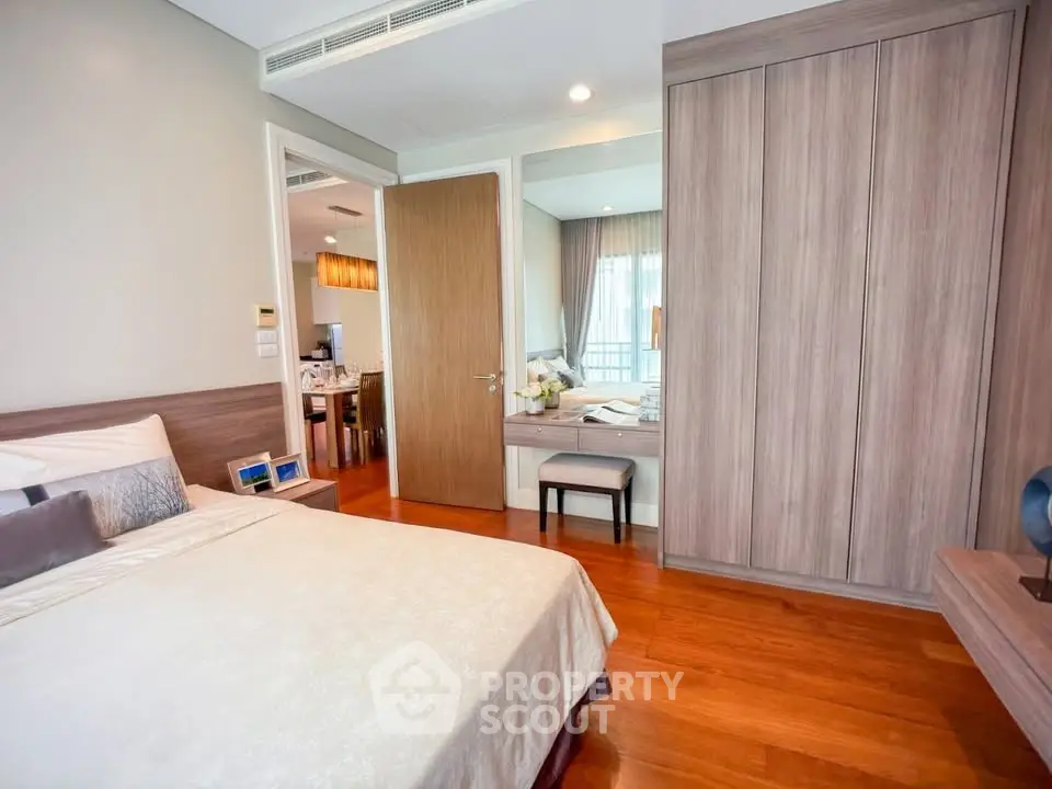 Elegant bedroom with wooden flooring and built-in wardrobe in modern apartment