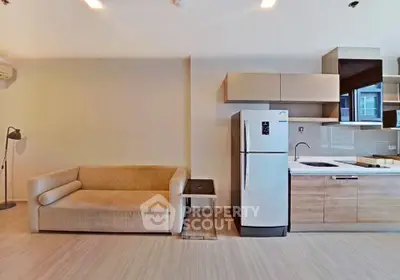 Modern open-layout living room with kitchen featuring sleek appliances and cozy sofa.