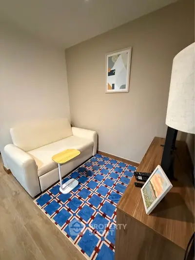 Cozy living room with modern decor, featuring a white sofa, colorful rug, and stylish wooden furniture.