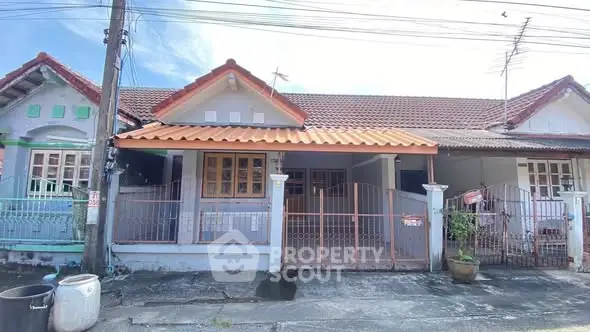Charming single-story house with tiled roof and gated entrance in a serene neighborhood.