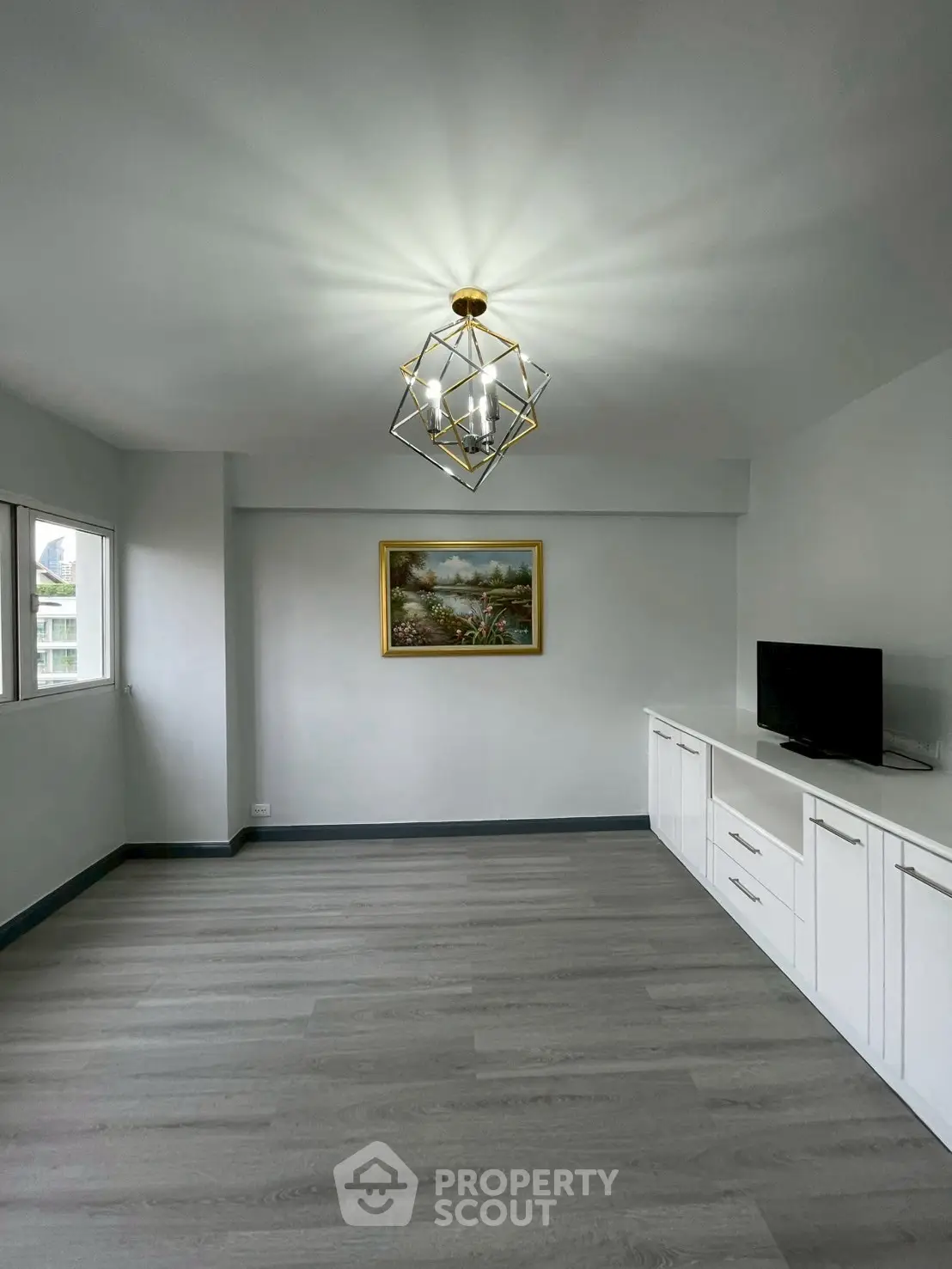 Spacious living room with modern chandelier and built-in storage, ideal for stylish living.