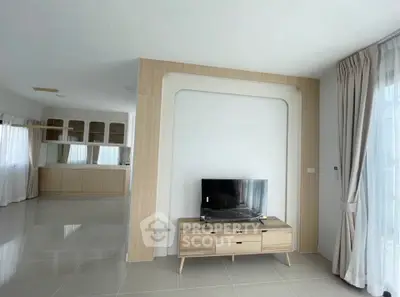 Spacious modern living room with sleek TV stand and open kitchen layout, featuring elegant floor-to-ceiling curtains.