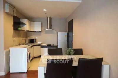 Modern kitchen with dining area, featuring washing machine and fridge in open layout.