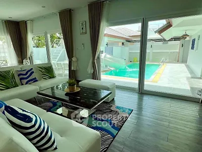 Luxurious living room with pool view, modern decor, and large windows in a stylish home.