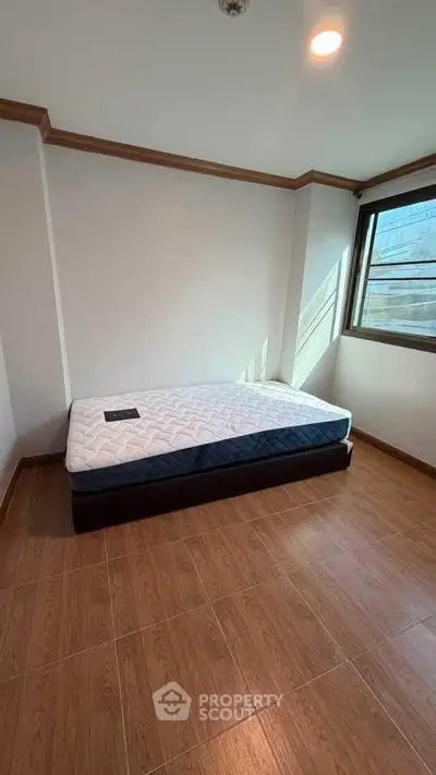 Spacious bedroom with natural light and wooden flooring