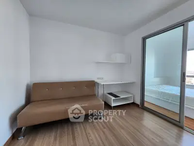 Modern minimalist living room with sleek brown sofa and sliding glass door to bedroom.