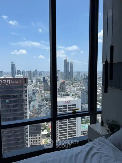 Stunning cityscape view from a high-rise apartment bedroom window, showcasing urban skyline and blue skies.