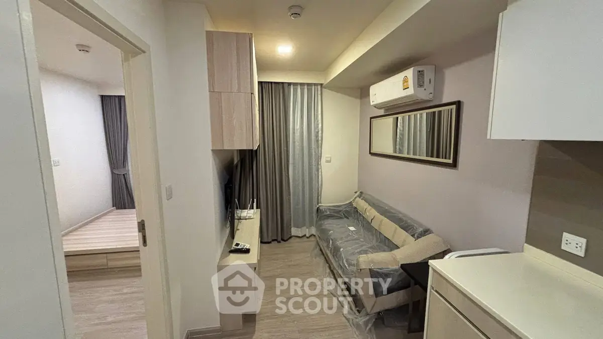 Modern apartment interior with cozy living room and adjacent bedroom, featuring sleek furniture and neutral tones.