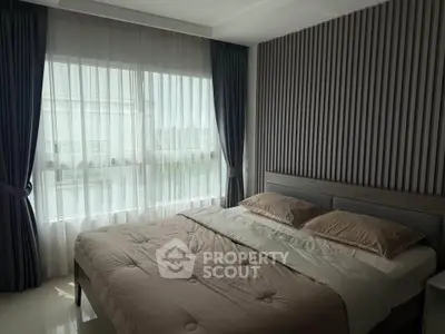 Modern bedroom with stylish decor and large window offering natural light
