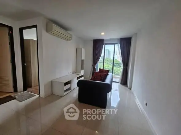 Spacious living room with modern sofa and city view from large window.