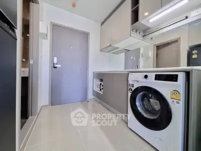 Modern kitchen with sleek cabinetry and built-in washing machine in stylish apartment.