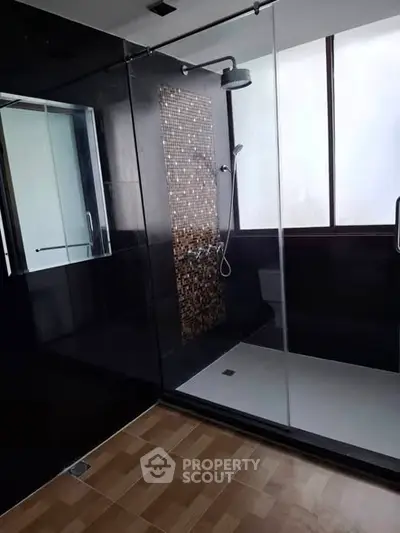 Luxurious modern bathroom with sleek black tiles and spacious shower area.