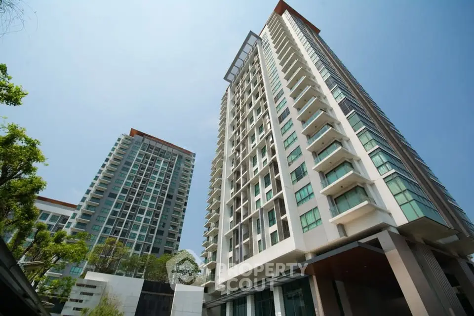 Stunning modern high-rise apartment buildings with lush greenery and clear blue sky.