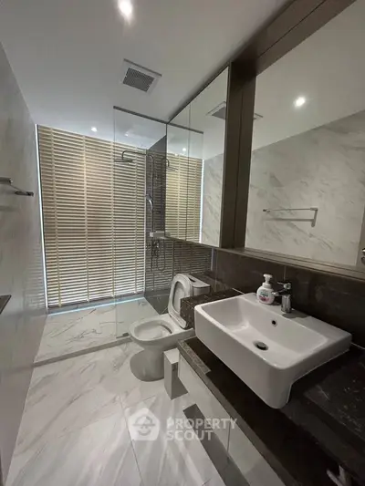 Modern bathroom with sleek design, featuring a glass shower and stylish sink.