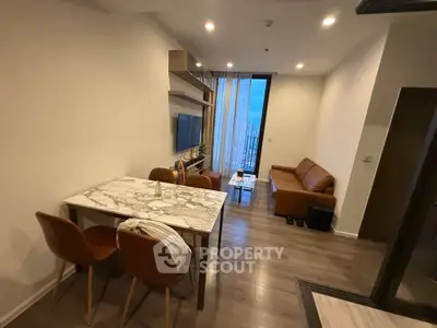 Modern living room with marble dining table and cozy seating area, featuring elegant lighting and wooden flooring.