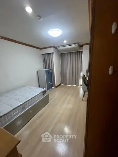 Cozy bedroom with wooden flooring, single bed, and air conditioning.