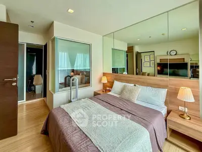 Modern bedroom with stylish decor and mirrored wall, featuring cozy bedding and ambient lighting.