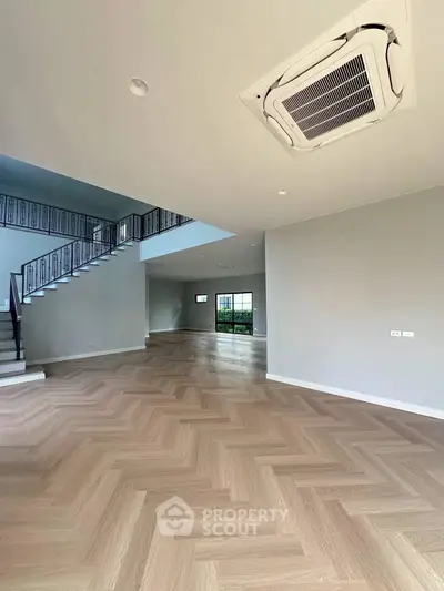 Spacious modern living room with elegant staircase and herringbone flooring