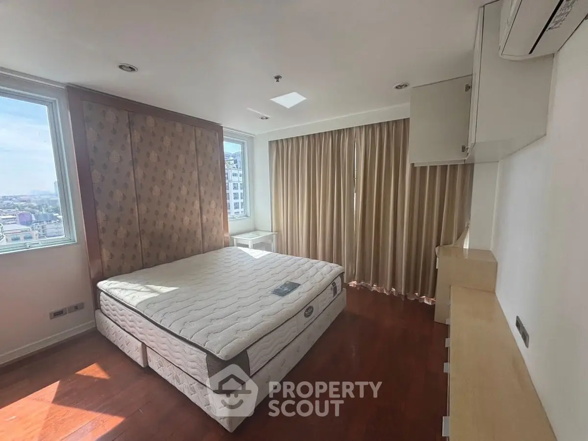 Spacious bedroom with large windows and elegant wooden flooring