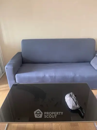 Modern living room with sleek black glass coffee table and comfortable blue sofa.