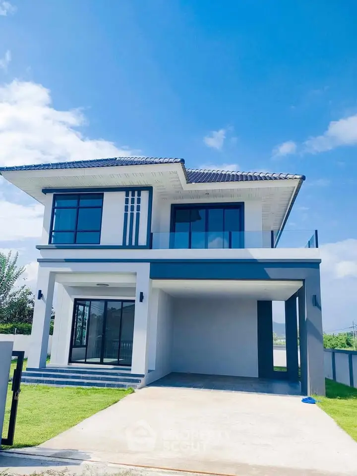 Modern two-story house with sleek design and spacious driveway under clear blue sky.