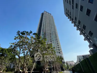 Stunning high-rise building with lush greenery and clear blue sky, perfect for urban living.