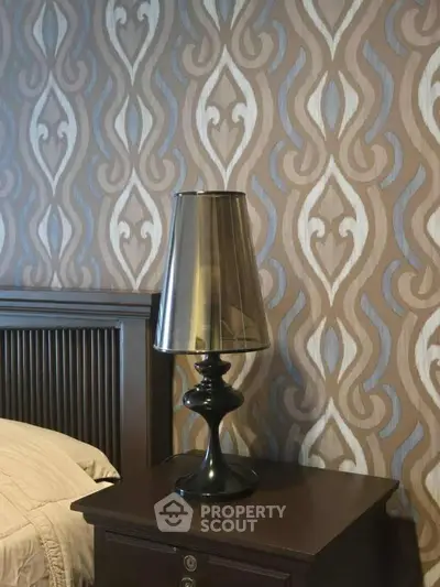 Elegant bedroom with stylish lamp and patterned wallpaper