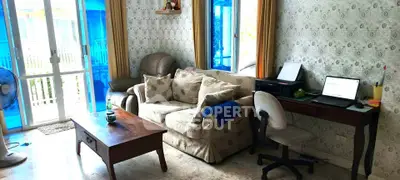 Cozy living room with sofa, desk, and large windows for natural light.