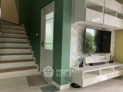 Modern living room with stylish TV setup and elegant staircase